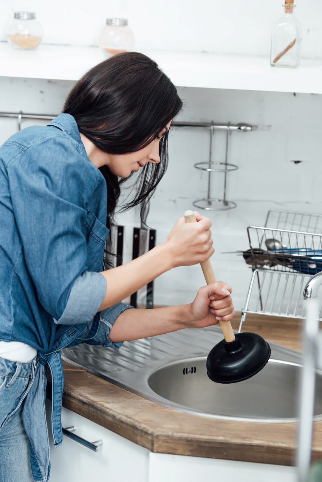 woman using plunger while fixing sink